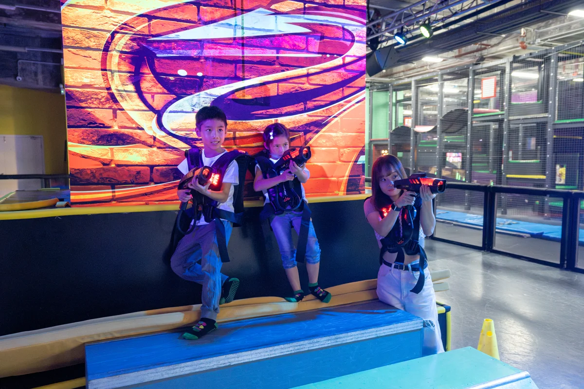 An adult and two children playing laser tag at Super Sports Park